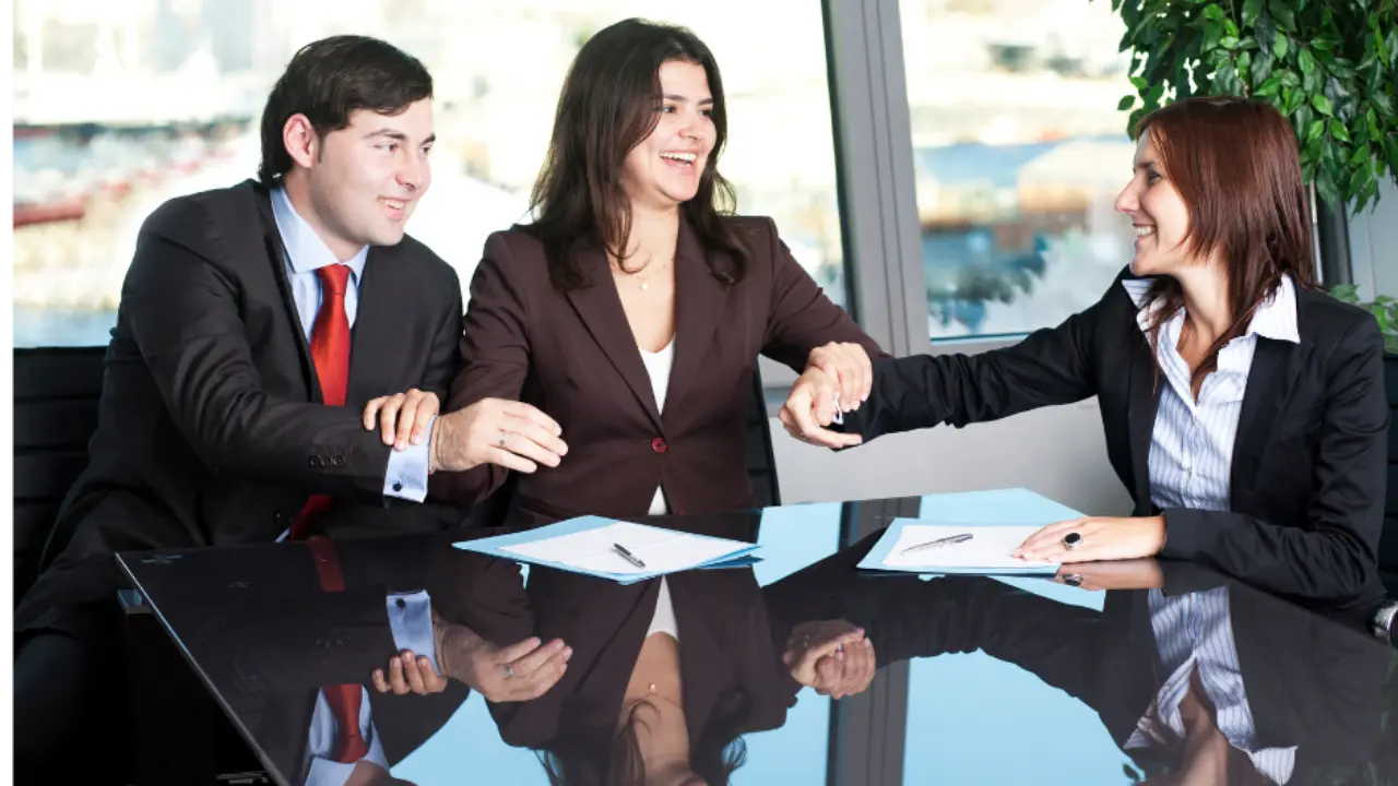 Image of three people holding hands smiling at each other.