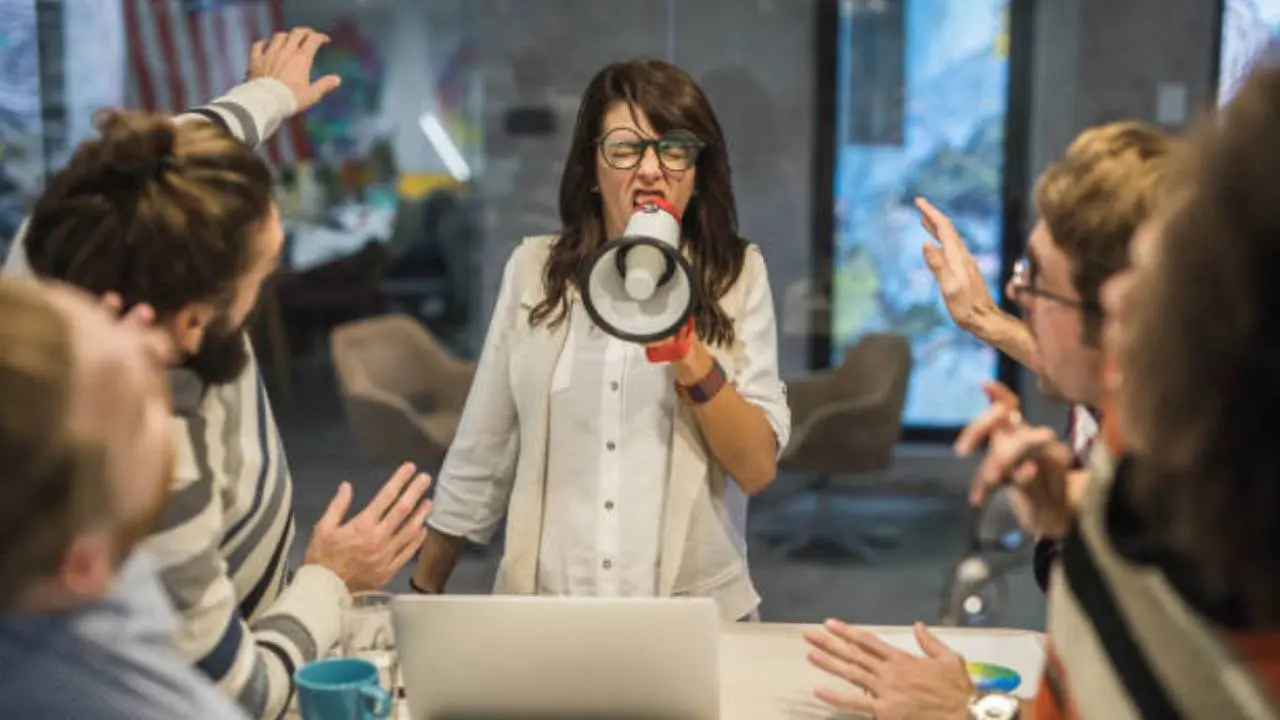 Image of a woman yelling at her workers with a horn.