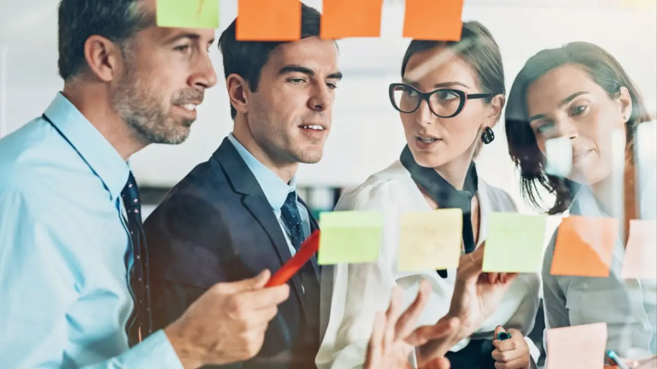 Image of 4 people at a blackboard talking.